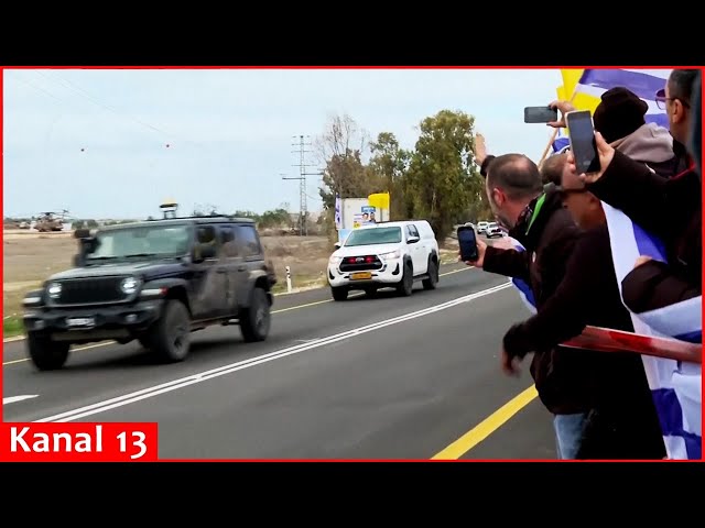 People standing by the road welcome captives who are happily returning to Israel