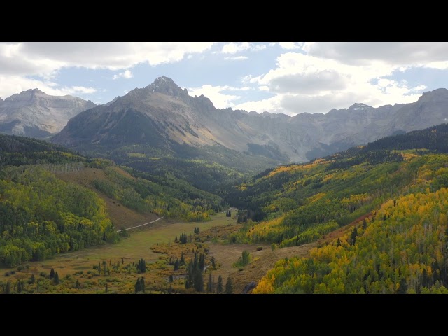 Aerial shot forward of beautiful colorado mountains and bright yellow and orange aspen trees