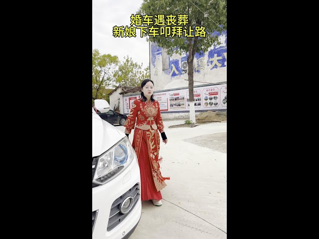 The wedding car meets the funeral by chance  and the bride gets off the bus and kneels down for thr