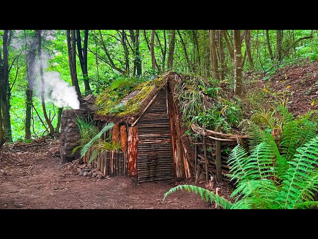 Building survival shelter with a fireplace. Bushcraft earth hut, moss roof & fireplace made of mud