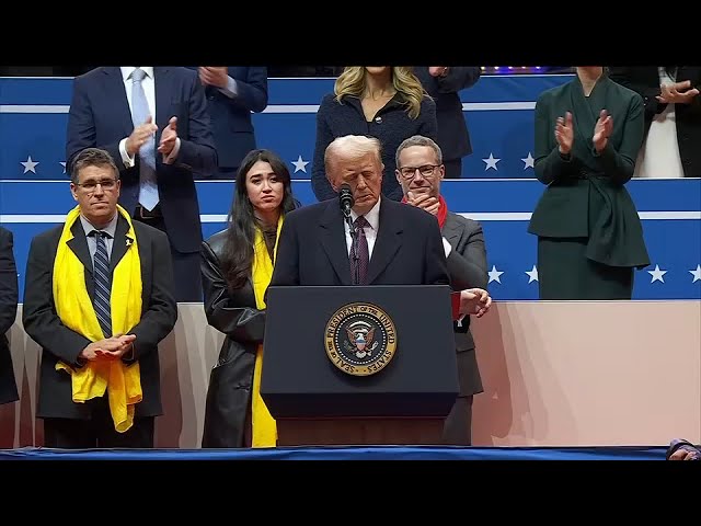 President Trump signs executive orders in front of supporters during arena address