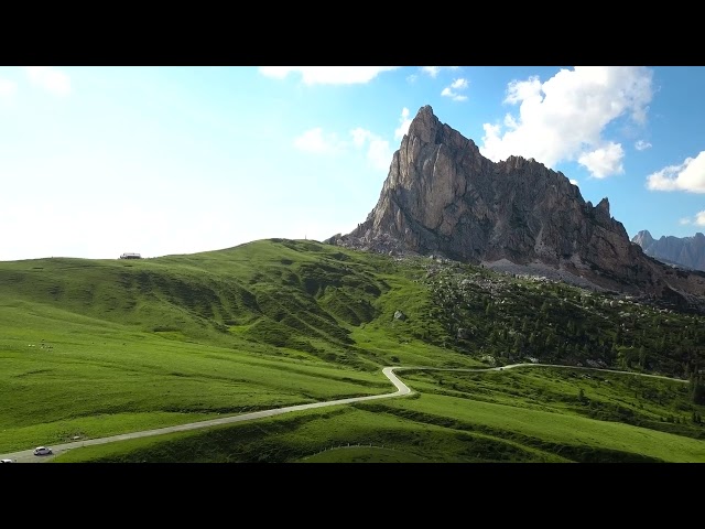 Small country road up in the mountains towards a high cliff, passo di giau, alps FREE STOCK VIDEO