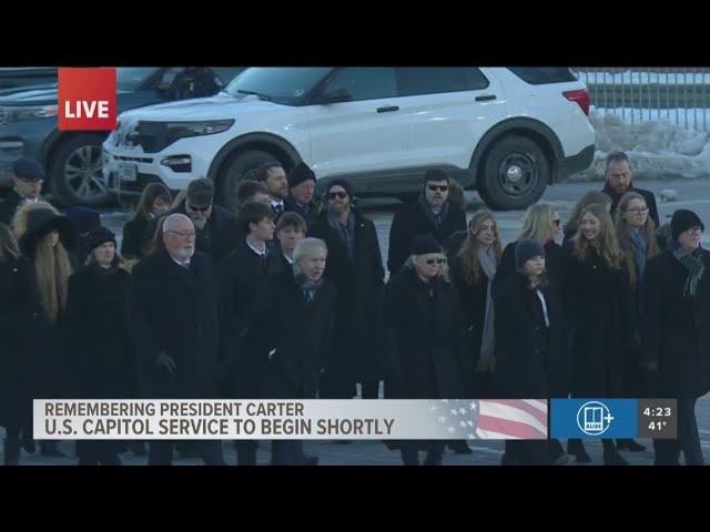 Carter family walks alongside horse-drawn carriage | Honoring President Jimmy Carter