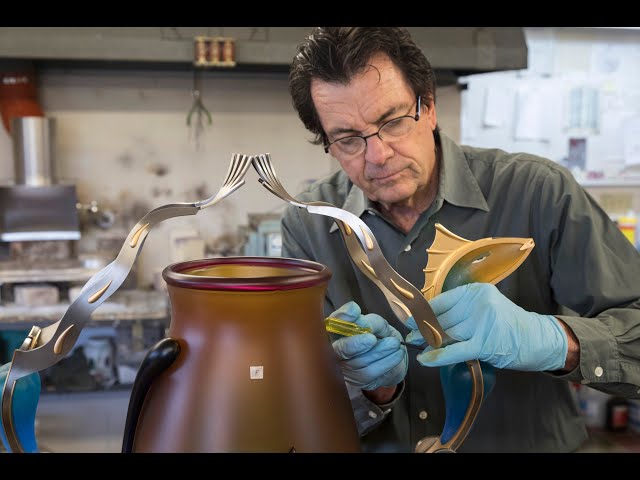 Artist Dan Dailey builds a large glass and metal vase in his studio